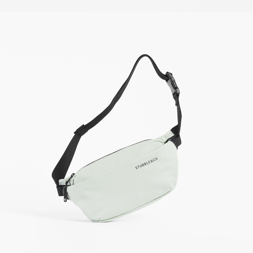 A studio shot showing a Crossbody in Soft Mint hanging by its strap