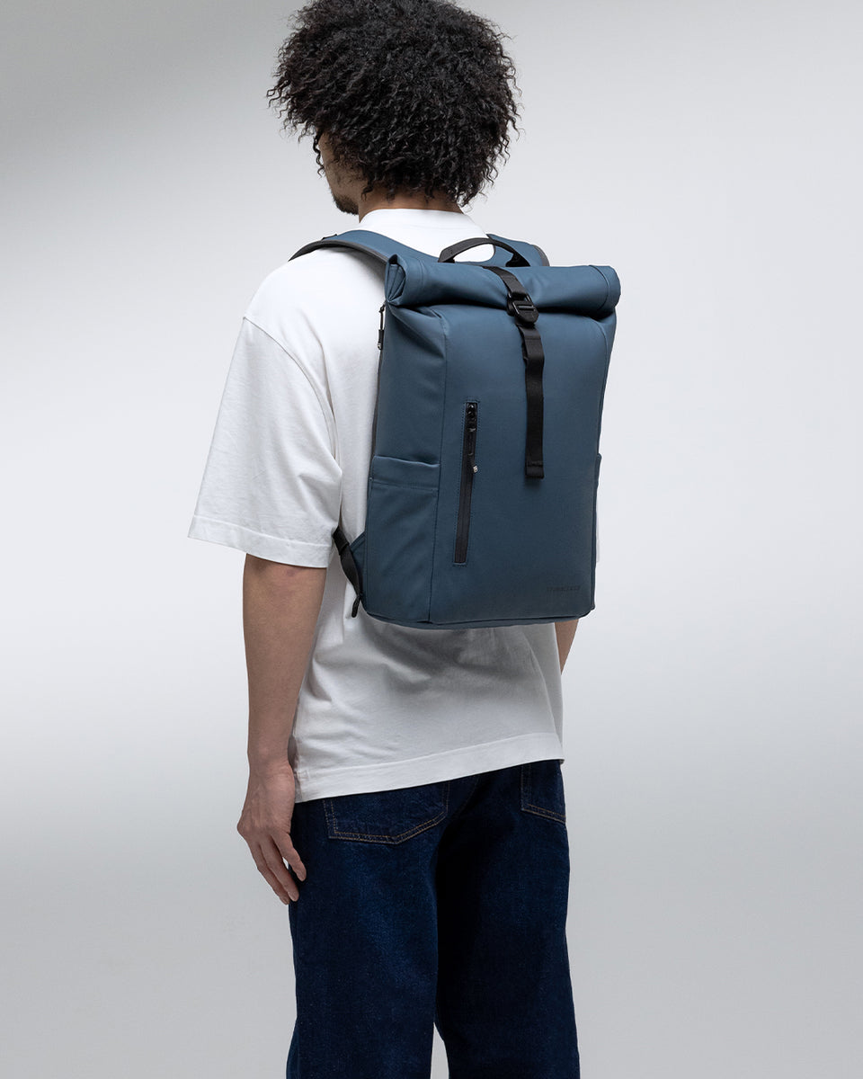 A man wearing a Roll Top 15L in Tasmin Blue on his back